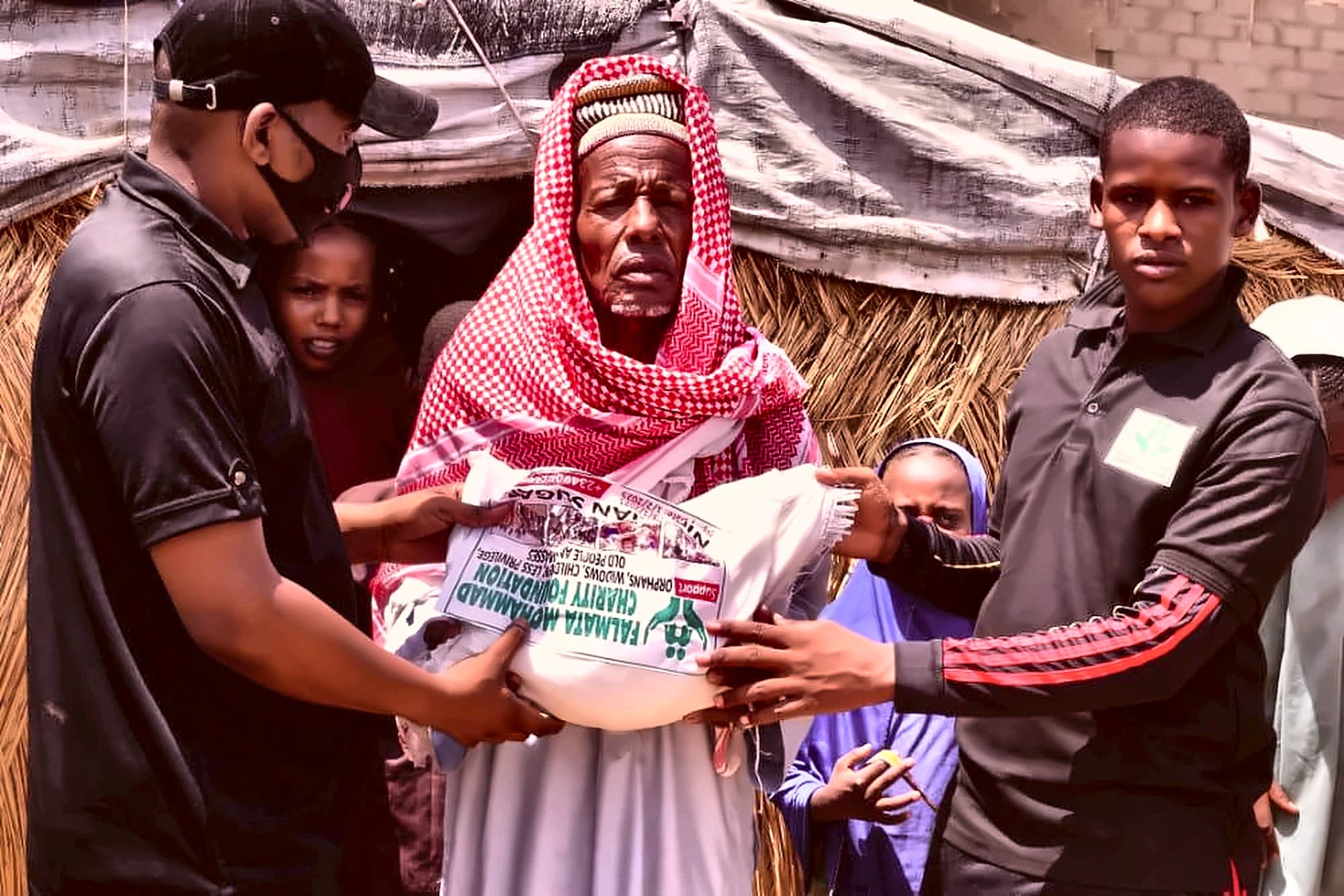Volunteers handing a food parcel to a mother during a relief distribution
